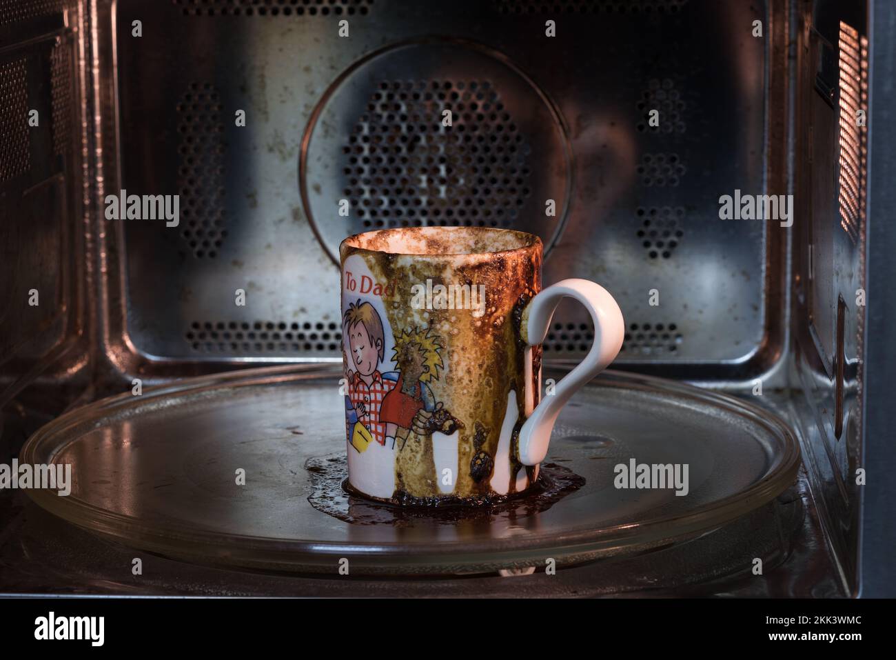 Verschüttetes Kaffeegetränk lief in der Mikrowelle über und verursachte so ein großes Chaos, das weggeräumt wurde, weil es vergessen wurde, und legte die falsche Einstellung ein, um zu viele Dinge beim Multitasking zu jonglieren Stockfoto