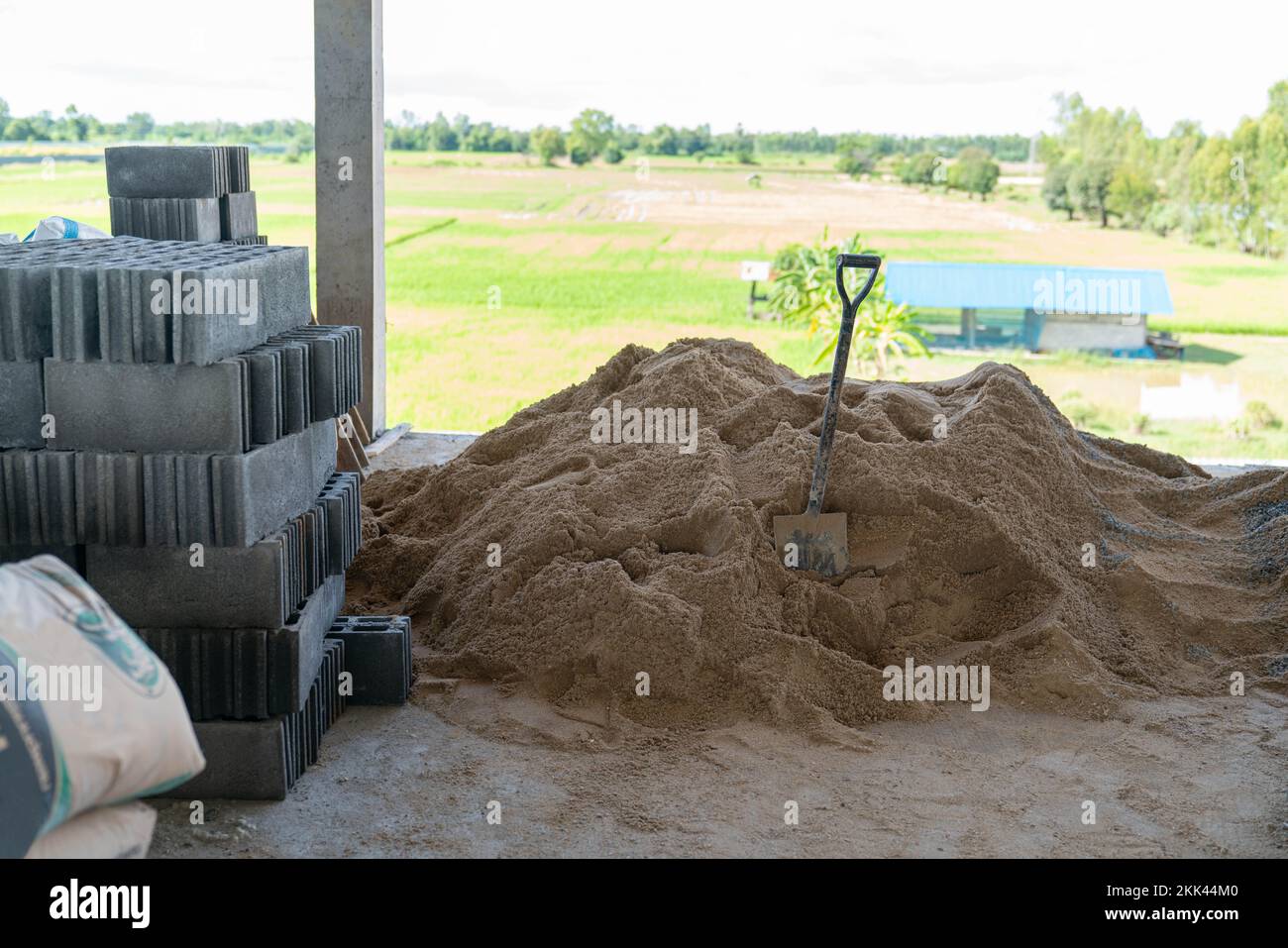 Mauerwerk und Schaufel auf Sandhaufen auf Baustelle. Betoninnenkonstruktion. Stockfoto