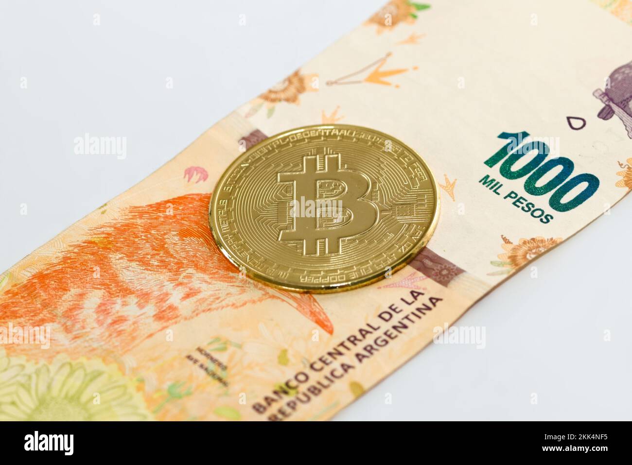 Physische Bitcoin über ein argentinisches Pesos-Gesetz auf weißem Hintergrund. Kryptowährungsumtausch, Investitionskonzept. Stockfoto