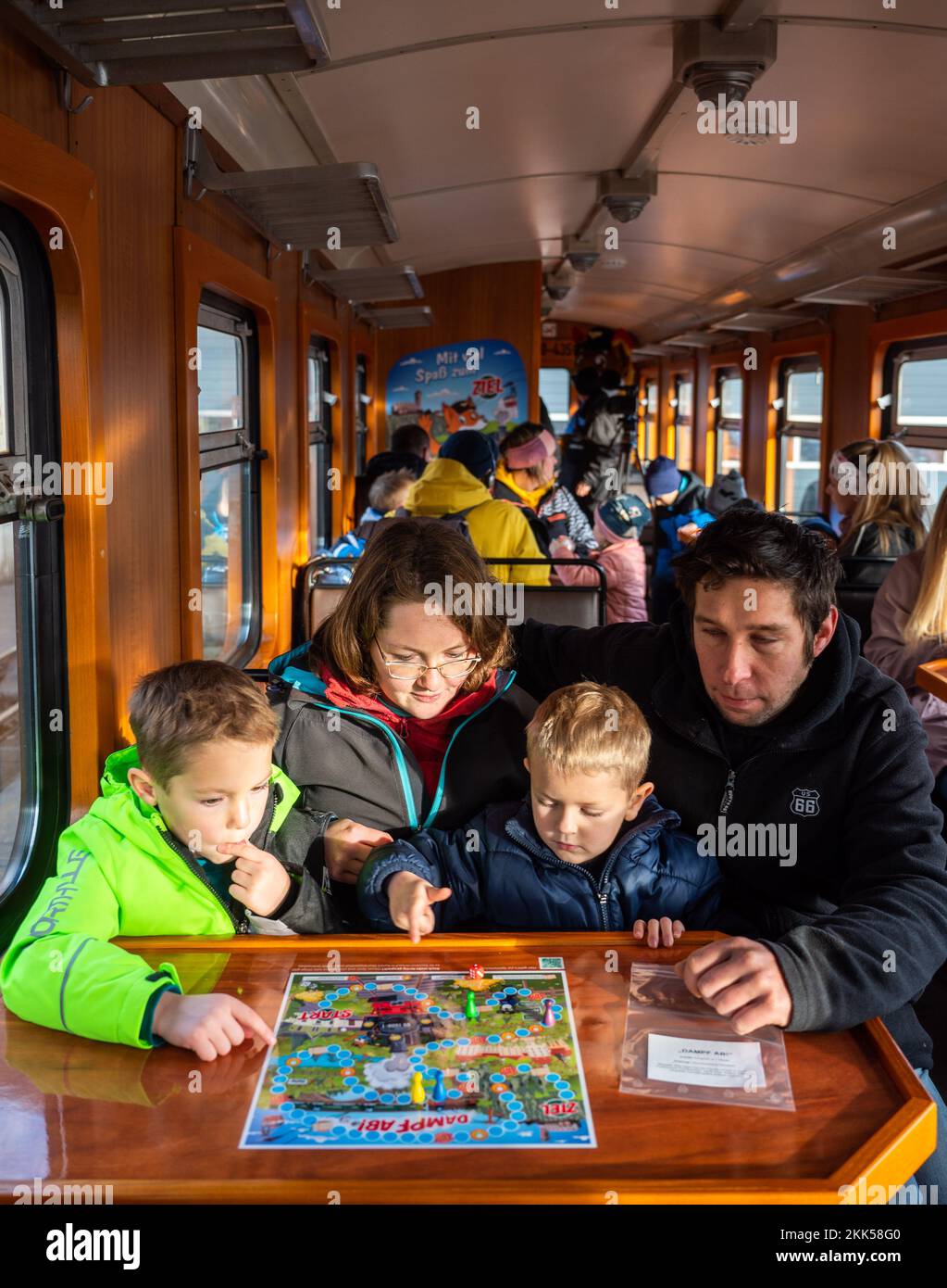 Oberwiesenthal, Deutschland. 25.. November 2022. Die Brüder Leon (6, l) und Jacob (4) spielen das Spiel „Dampf ab!“ Mit ihren Eltern Anja und Johannes frei während der Inbetriebnahme des neuen Sportwagens der Fichtelbergbahn. Es ist der erste Wildwaggon auf einer Schmalspurbahn in Sachsen. Die sächsische Dampfeisenbahngesellschaft (SDG) investierte 11.500 Euro in die Umrüstung und Konstruktion des Autos. Kredit: Kristin Schmidt/dpa/Alamy Live News Stockfoto