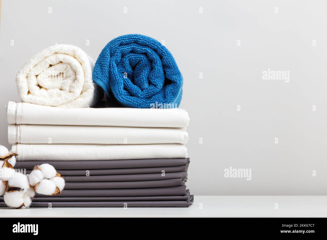 Ein Stapel Bettwäsche, Rollen mit blauen und weißen Handtüchern auf dem Tisch. Stockfoto
