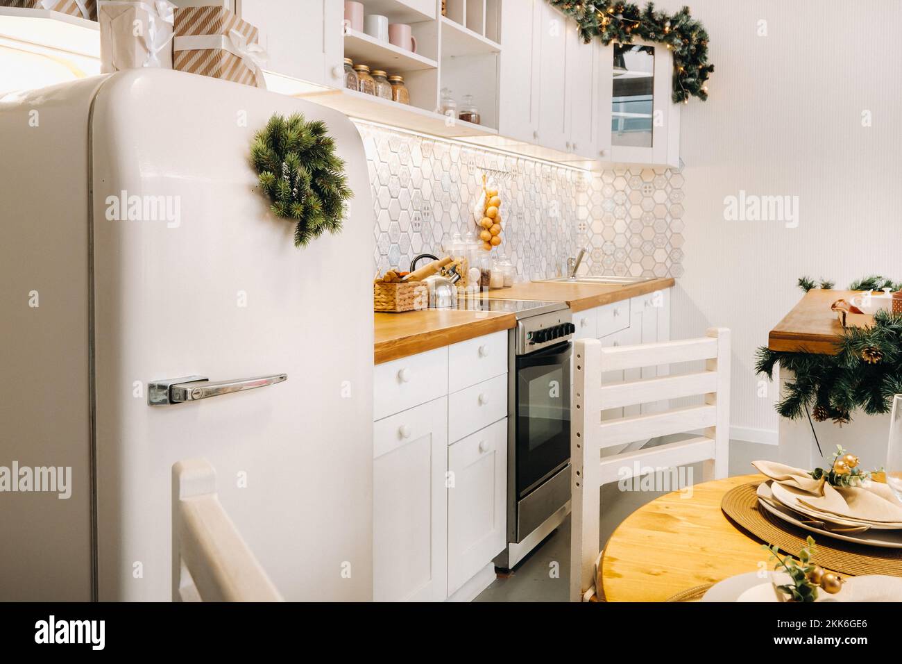 Weihnachtstischdekoration in der Küche, Banketttisch mit Gläsern vor dem Servieren des Essens, Nahaufnahme des Weihnachts-Dinner-Tisches mit saisonalen Stockfoto