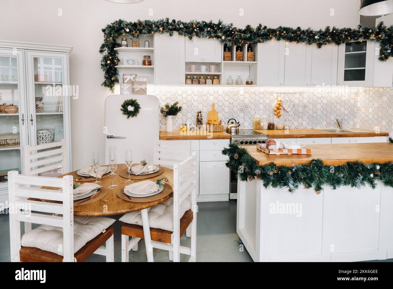 Weihnachtstischdekoration in der Küche, Banketttisch mit Gläsern vor dem Servieren des Essens, Nahaufnahme des Weihnachts-Dinner-Tisches mit saisonalen Stockfoto