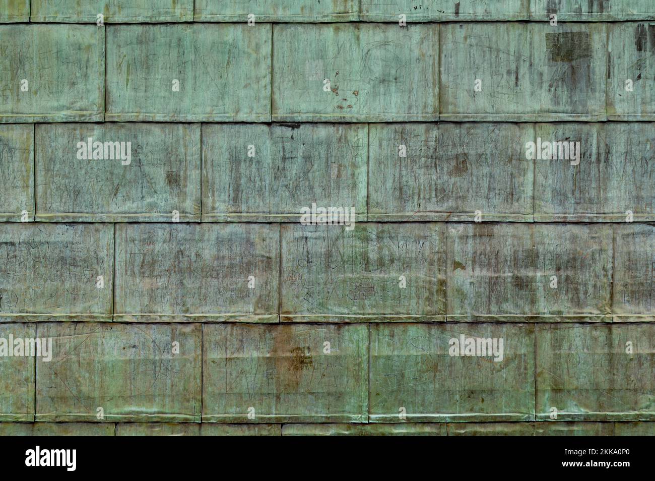 Gefaltete Bleche aus oxidiertem Kupfer auf dem Dach. Hintergrund mit Kupferwandtextur mit Spuren und Schürfwunden. Stockfoto