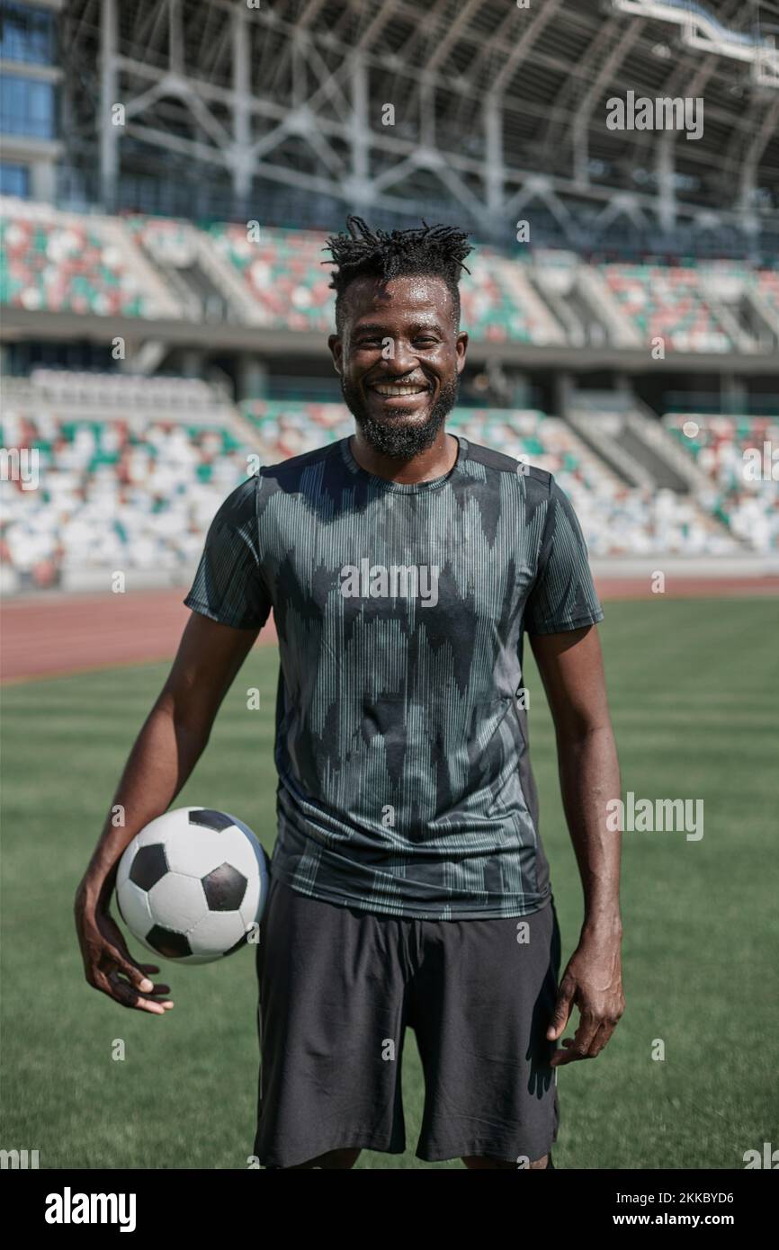 Ein junger Mann steht in einem Stadion mit einem Fußball in der Hand Stockfoto