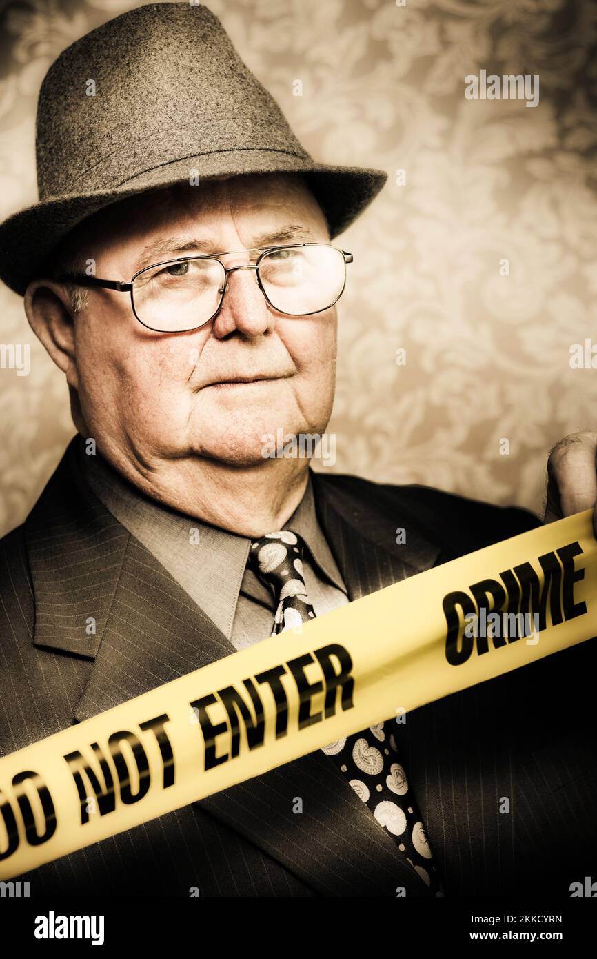 Vintage-Porträt eines älteren Detektivs für scharfsinnige Verbrechen mit einem Aufmerksamer Blick in sein Auge, der aufmerksam zuschaut, wie er steht Hinter dem Band bei einem Verbrechen Stockfoto