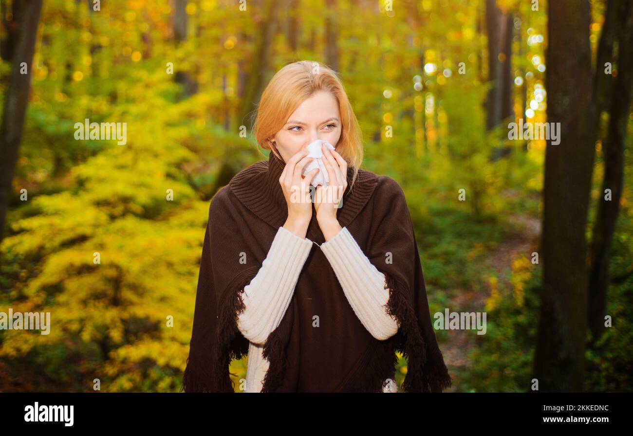 Eine Frau, die im Herbstpark Nase mit Taschentuch bläst. Saisonale Virusinfektion. Chronische Krankheit Stockfoto