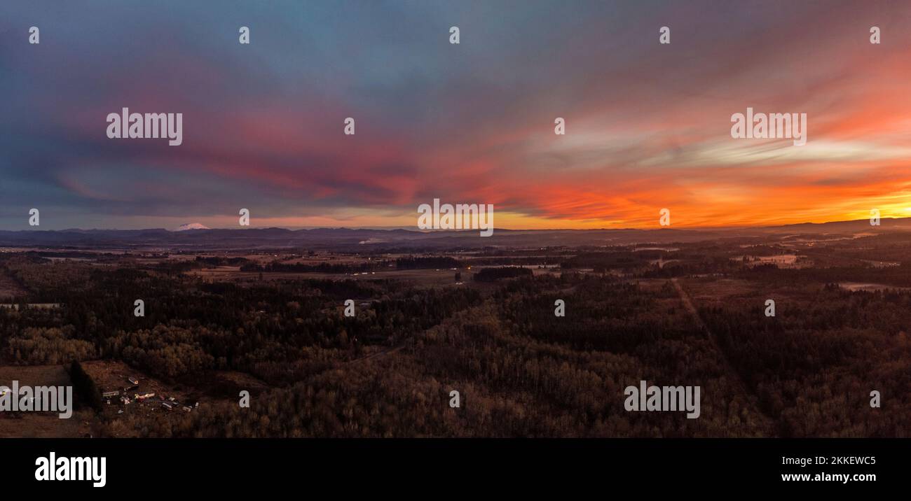 Luftdrohnenfoto des dramatischen Sonnenuntergangs über der Landschaft des Bundesstaats Washington mit Mt. St. Helens von links Stockfoto