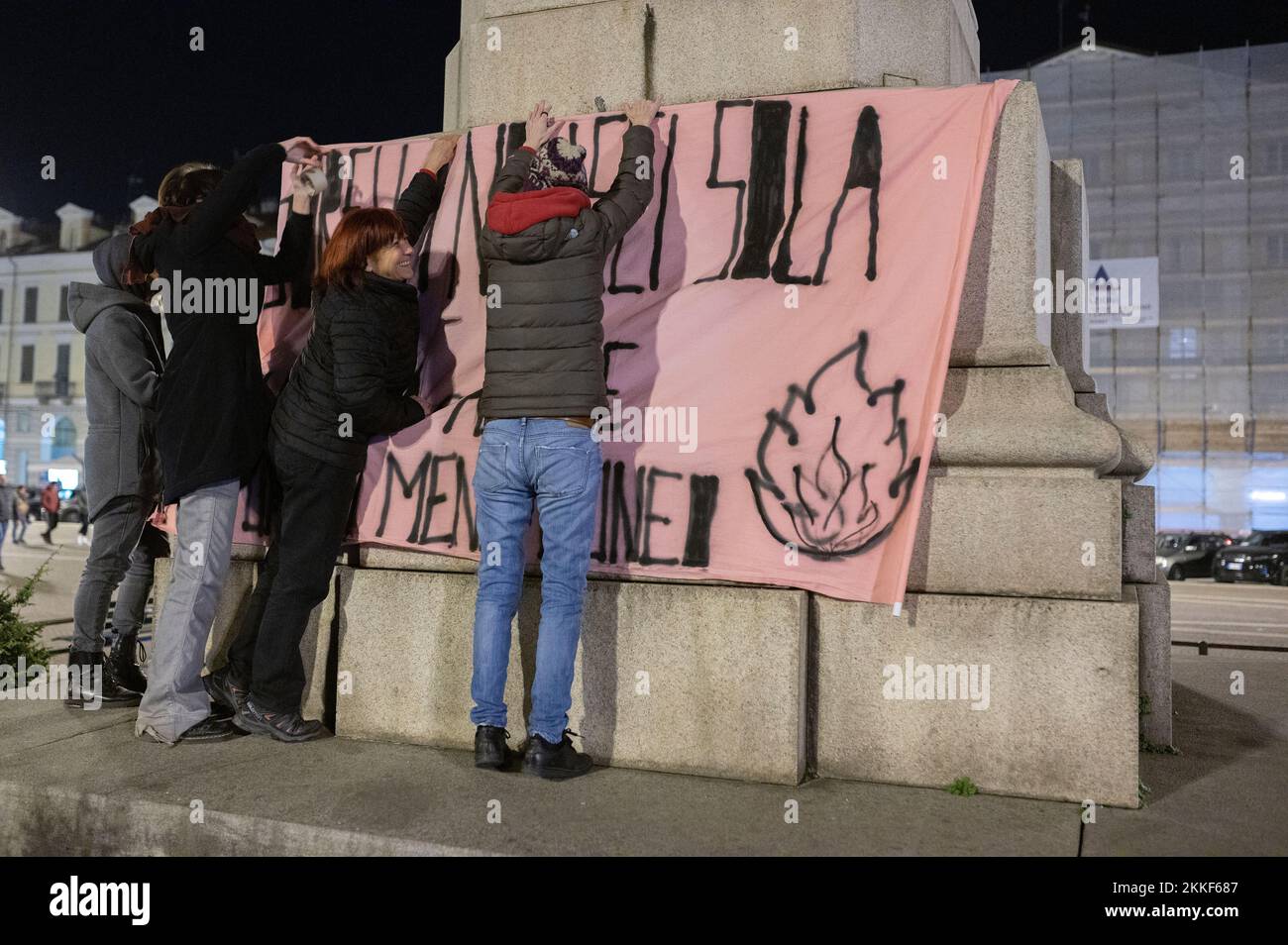 Cuneo, Italien. 25.. November 2022 Eine Gruppe von Demonstranten hängt ein Protestbanner an ein Denkmal der Stadt, um den Welttag gegen Gewalt gegen Frauen zu begehen. Das Phänomen der Gewalt gegen Frauen nimmt in Italien zu. Kredit: Luca Prestia / Alamy Live News Stockfoto
