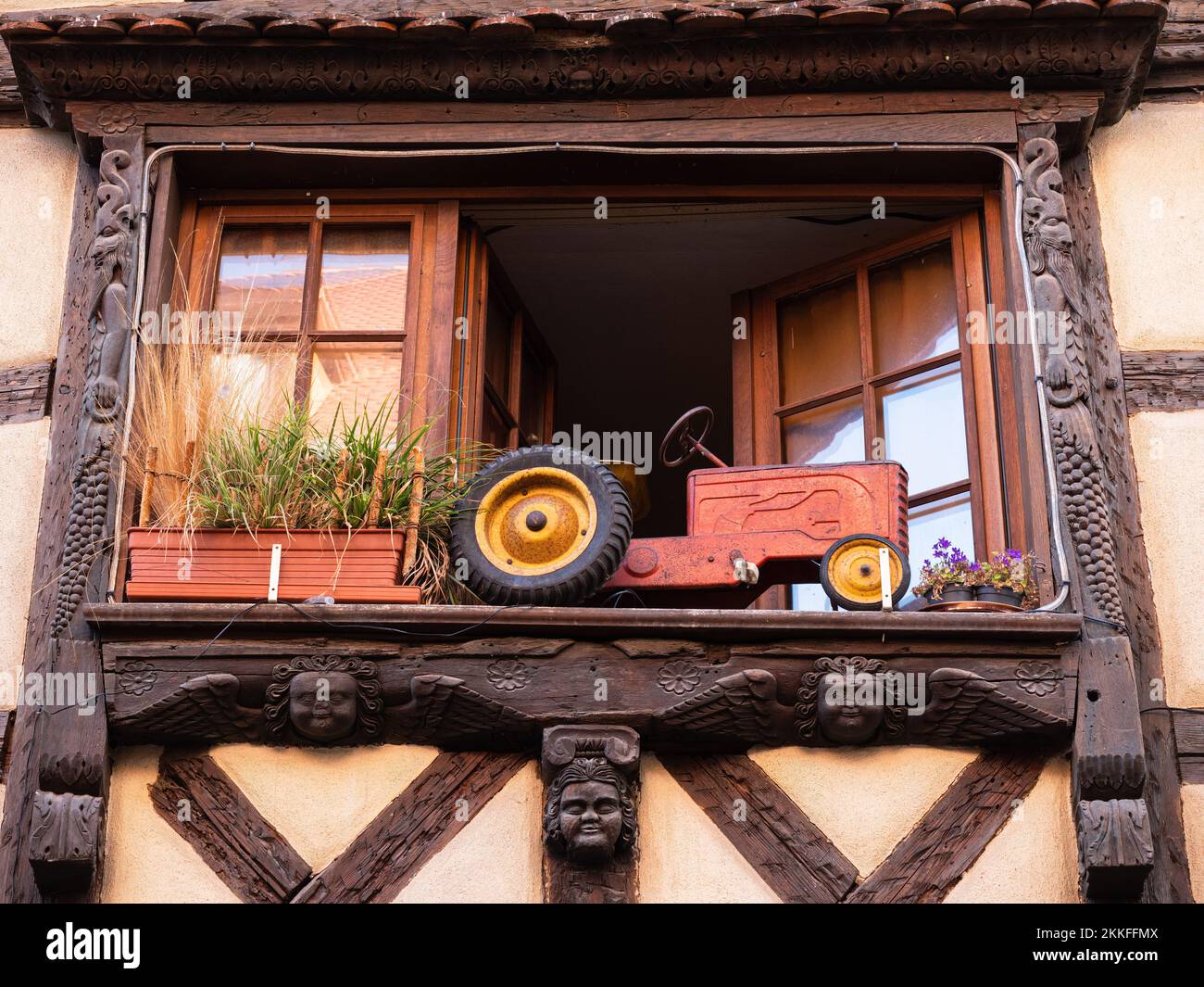 Riquewihr, Frankreich - 12. Oktober 2022: Rotes Traktormodell im Fenster des traditionellen Hauses im Elsass Stockfoto