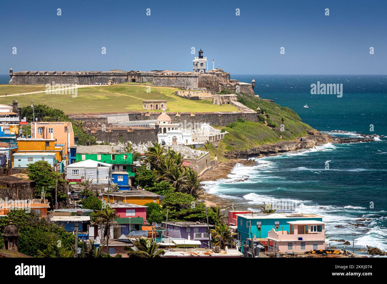 Farbenfrohe Häuser mit El Morro Fort und Leuchtturm in der Ferne in Old San Juan auf der tropischen Karibikinsel Puerto Rico, USA. Stockfoto