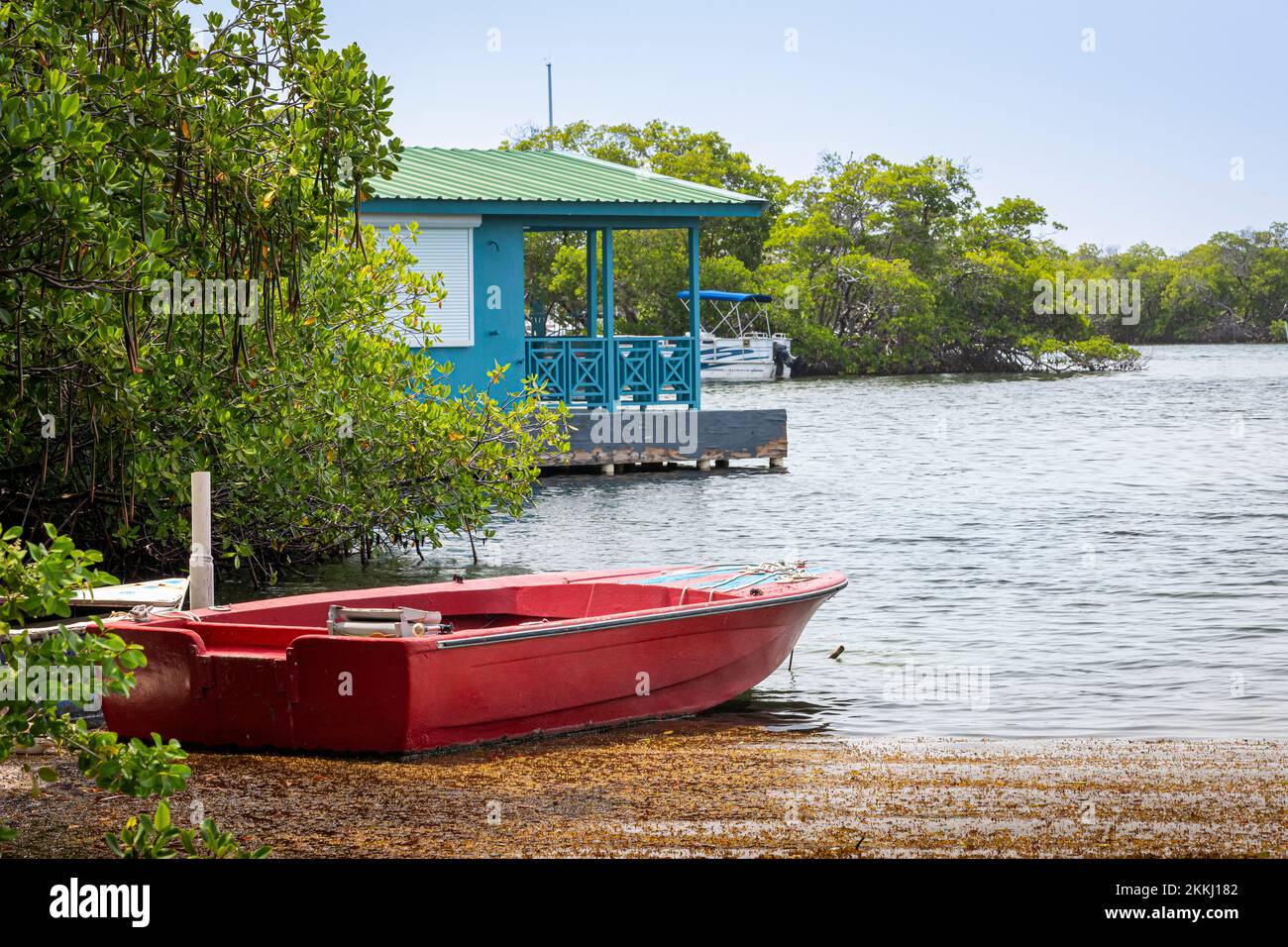Ein rotes Boot und ein blaues Bootshaus in La Parguera auf der tropischen karibischen Insel Puerto Rico, USA. Stockfoto