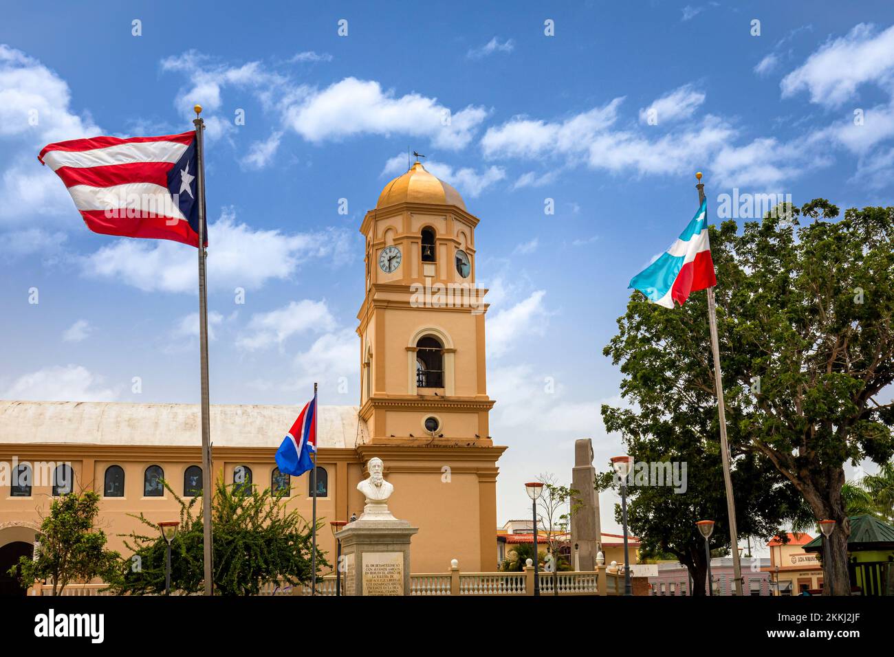 Die Puerto-ricanische Flagge und andere zieren die San Miguel Archangel Church plaza in Cabo Rojo auf der tropischen karibischen Insel Puerto Rico, USA. Stockfoto