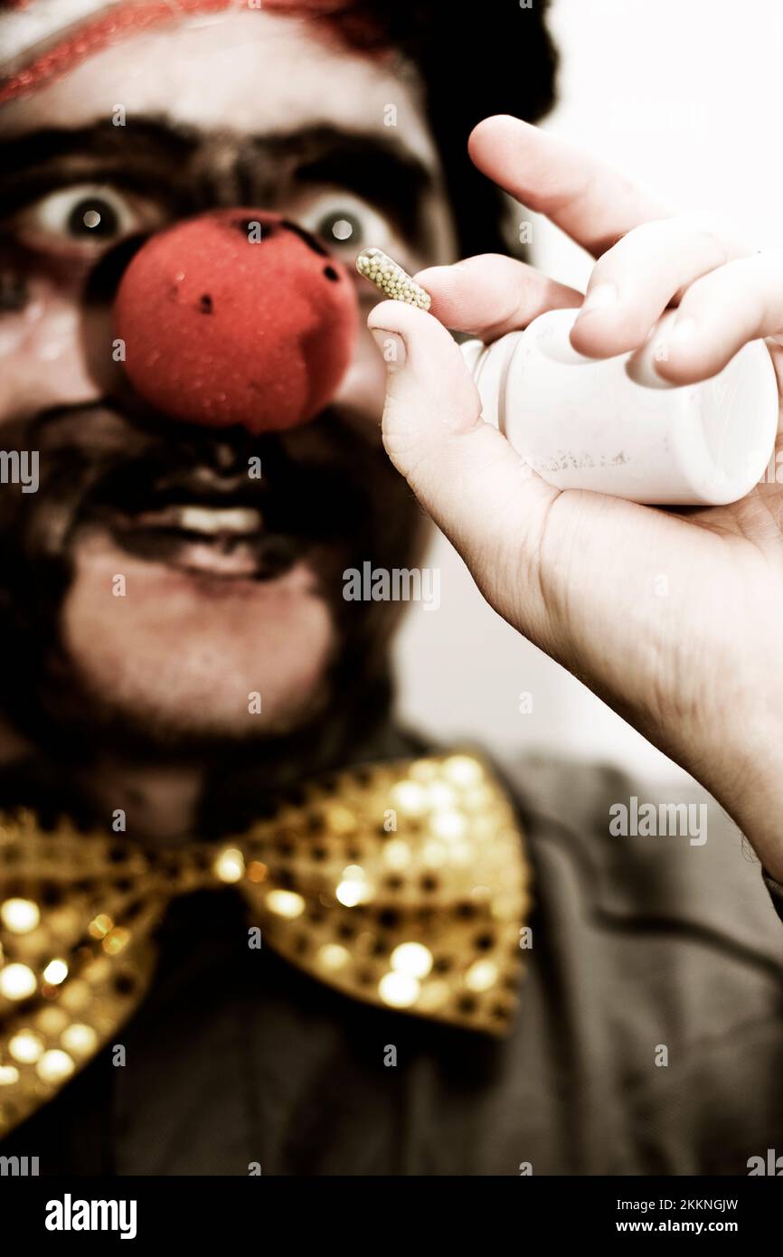 Dunklen Bild eines Clowns hält eine Tablette verordneten Medikamente dazu beitragen, sein Humor zurück Stockfoto