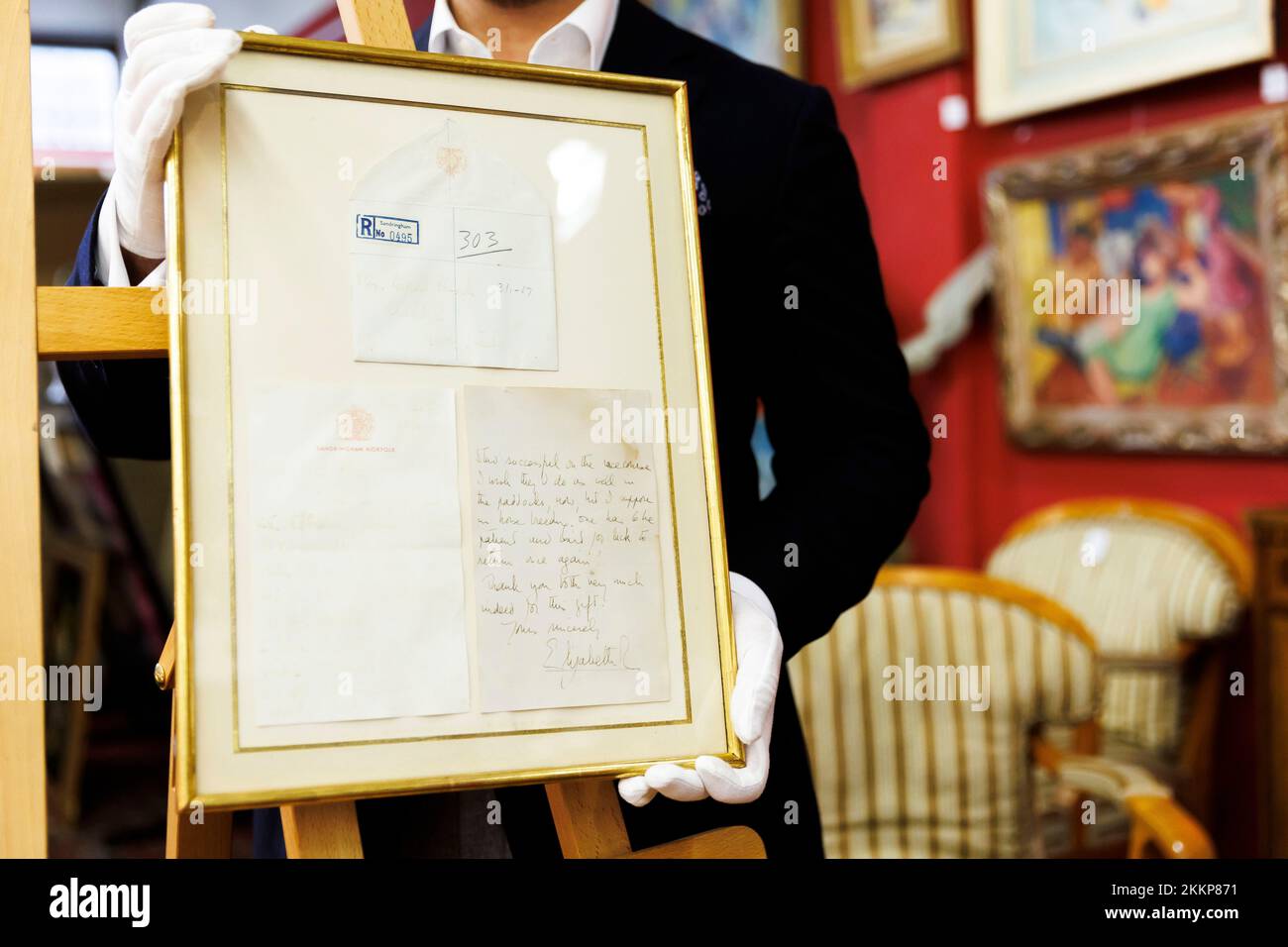 Leinfelden Echterdingen, Deutschland. 25.. November 2022. Das Stuttgarter Auktionshaus Eppli Auctions, neben anderen Objekten zum Thema „Britische Königsfamilie“, ein handgeschriebener zweiseitiger Brief der kürzlich verstorbenen Königin Elizabeth II (1926-2022) von 1966 an einen leidenschaftlichen Reiter. Ferdinand Eppli präsentiert das zu versteigernde Objekt. Es ist der gerahmte Brief, eine Kopie der Rückseite und der Umschlag. Kredit: Julian Rettig/dpa/Alamy Live News Stockfoto