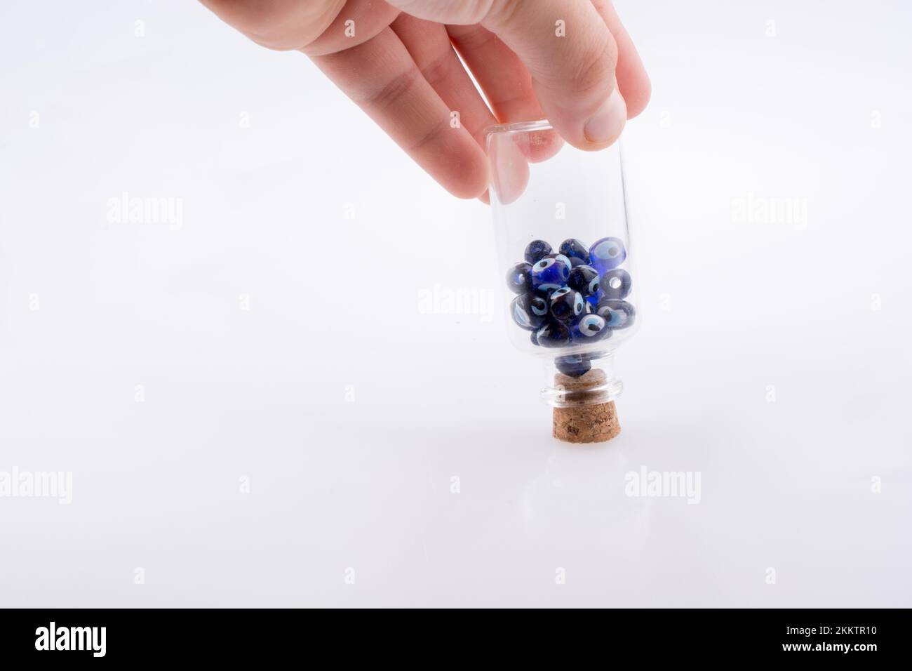 Kleine Glasflasche mit böser blauer Augenperle in der Hand Stockfoto