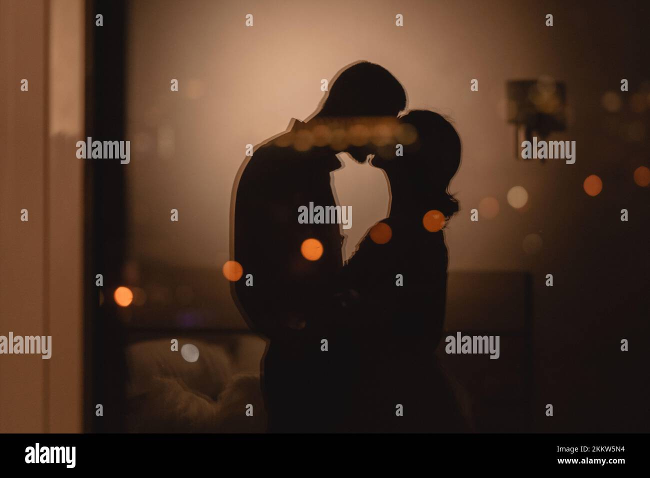 Reflexion im Fenster ein Paar, das sich liebt und sich mit Lichtern im Hintergrund küsst, eine romantische Nacht im Hotelkonzept Stockfoto