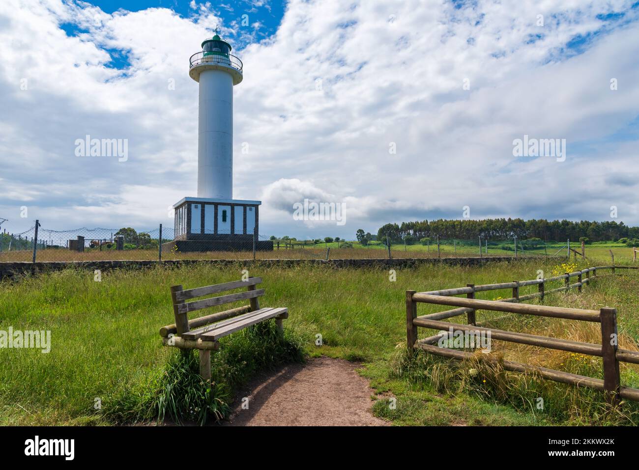 Leuchtturm von Lastres, Landschaft mit einer Holzbank und einem Zaun, umgeben von Gras und Bäumen. Stockfoto