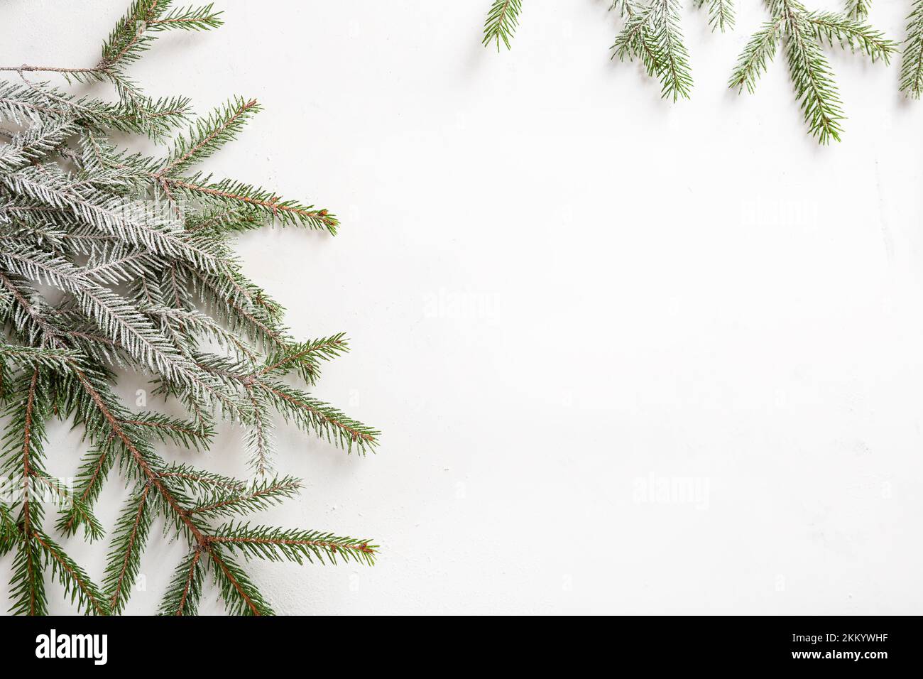 Weißer Urlaubshintergrund mit grünen verschneiten Zweigen und Kopienansicht von oben Stockfoto