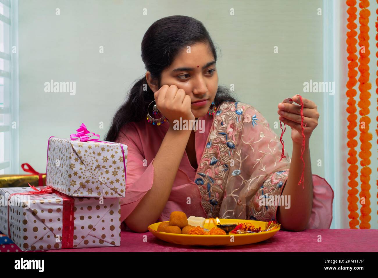 Schwester mit Pooja-Teller und Rakhi, die allein auf ihren Bruder anlässlich von Raksha Bandhan warten Stockfoto