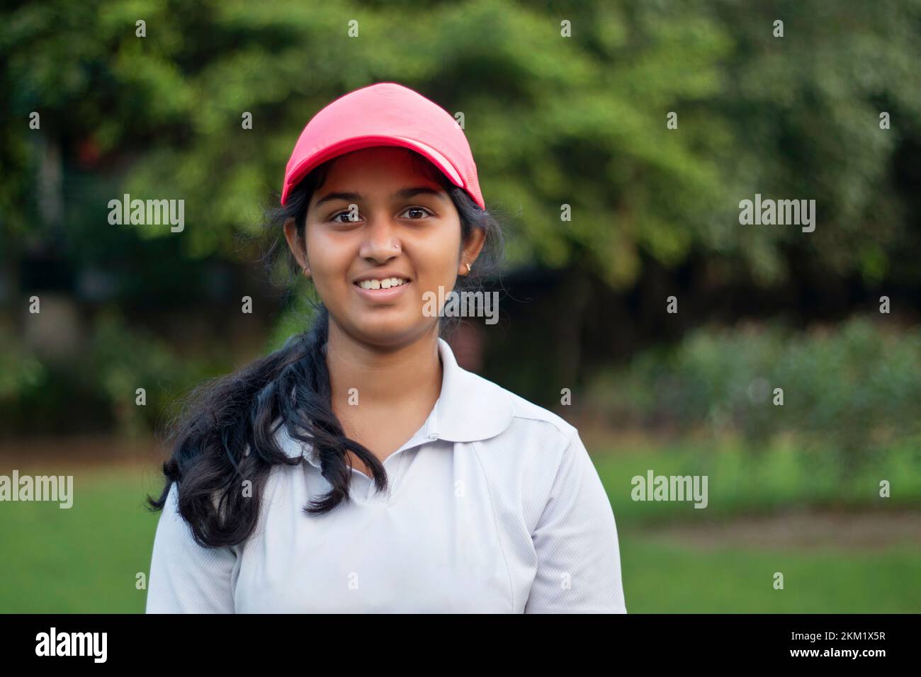 Ein Mädchen, das Cricket-Uniform trägt und draußen steht Stockfoto