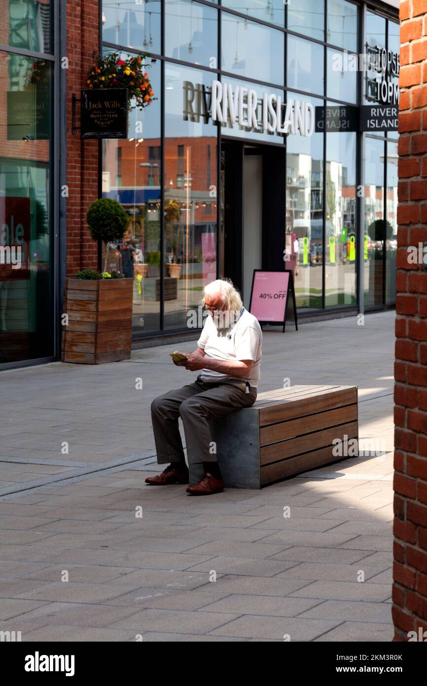 Ein Mann liest auf einer Bank im Old Market Shopping Centre, Hereford, Herefordshire Stockfoto