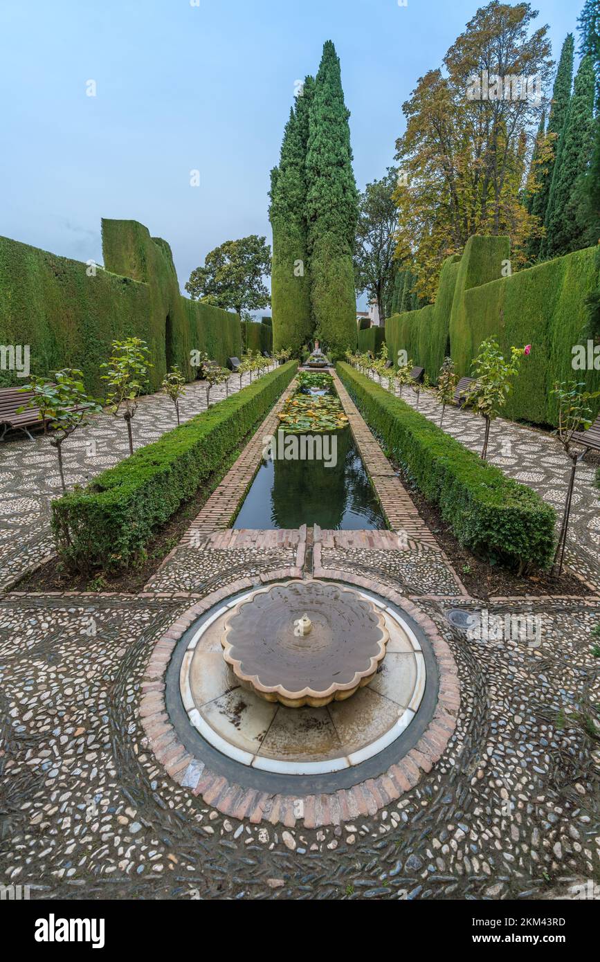 Granada, Spanien - 22. November 2022 : Springbrunnen und Pfad in den Gärten der Jardines del Generalife im Palastkomplex Alhambra. UNESCO-Weltkulturerbe. Stockfoto