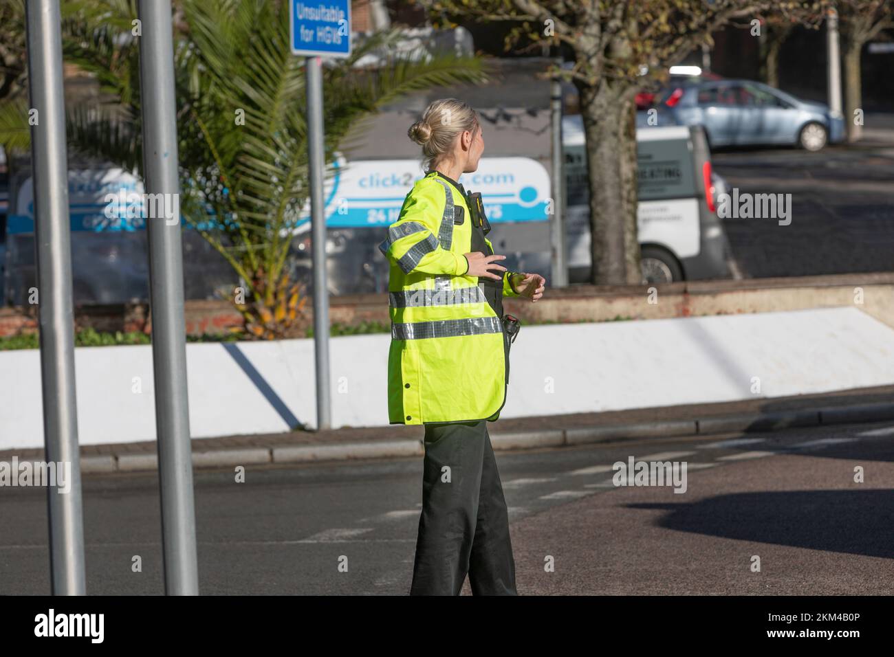 Eine junge Polizistin in einer Hi-Vis-Jacke, die den Verkehr leitet. Stockfoto