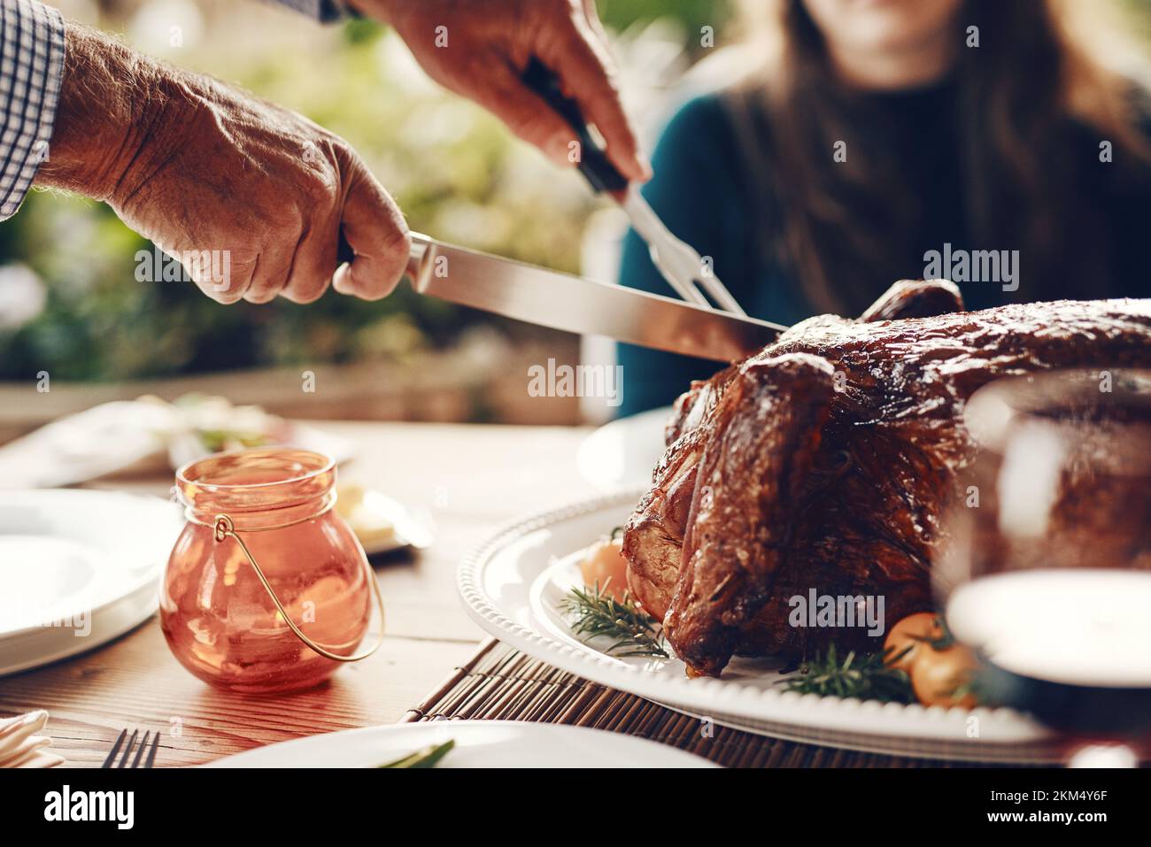 Truthahn, Thanksgiving und Hühnchen, die an einem Tisch für eine Familie in einem Heim oder bei einer Hausfeier von Hand geschnitten wurden. Party, Zoom und Mann mit Messerschnitt Stockfoto