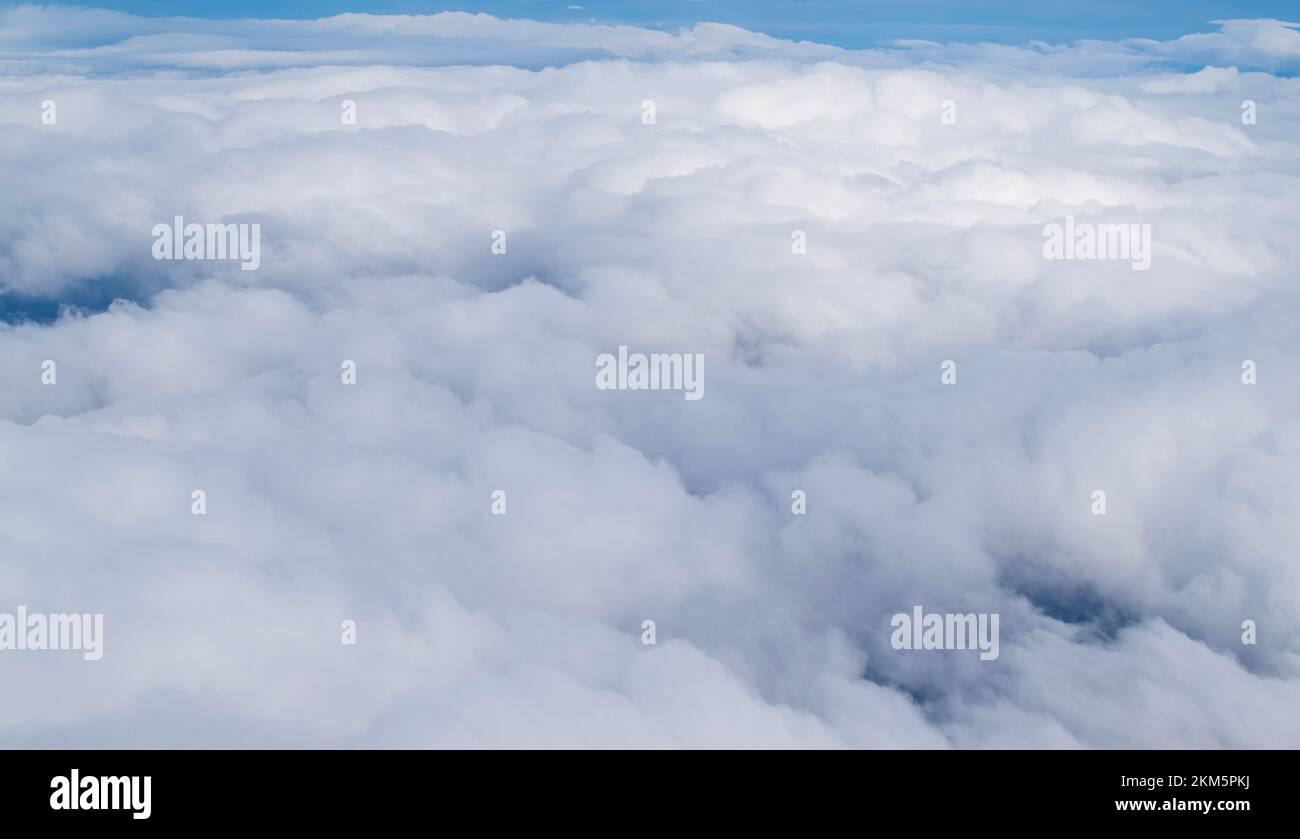 Blick auf flauschige Wolken, vom Fensterplatz des Flugzeugs aus gesehen. Stockfoto