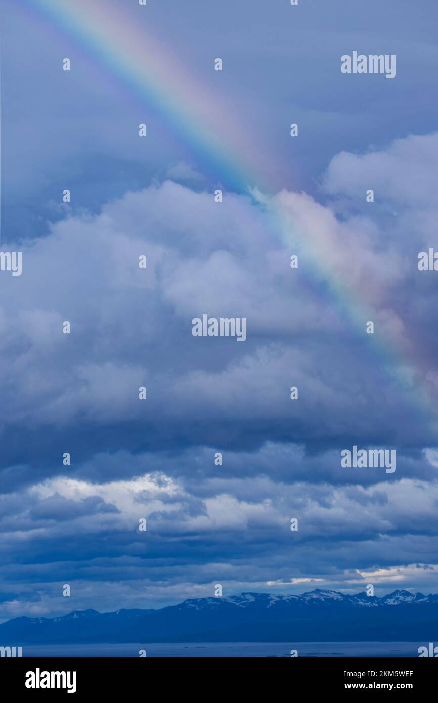 Nahaufnahme eines Regenbogens mit Bergen, Wolken und dem Ozean im Hintergrund. Stockfoto