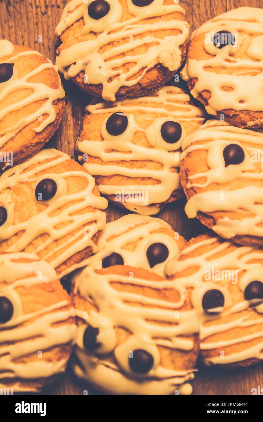 Stillleben Süßigkeiten Foto von einer erschreckenden Charge von Shortbread Kekse mit weißer Glasur und Schokoladenchips zum Aussehen dekoriert Wie Halloween Mumien Stockfoto