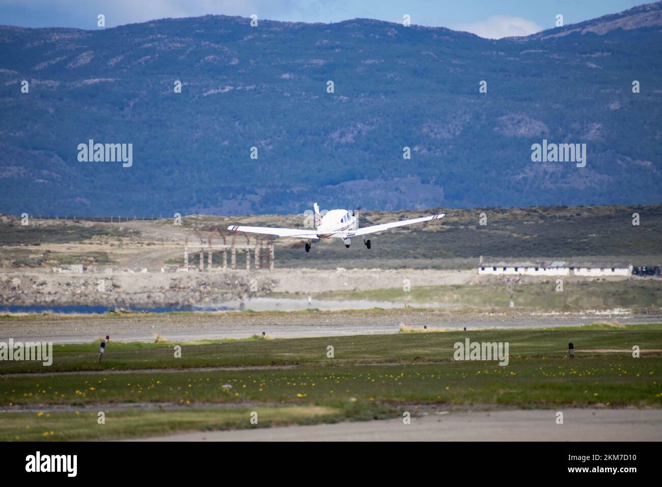 Ein kleines einmotoriges Flugzeug, das aus Ushuaia, Argentinien, startet. Mit Bergen im Hintergrund. Stockfoto