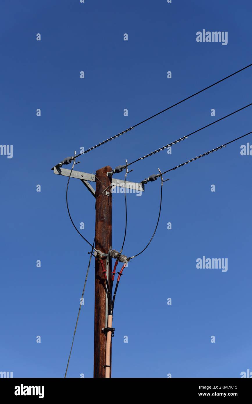 Überkopfkabel an einem Pfosten vor einem blauen Himmel. Stockfoto