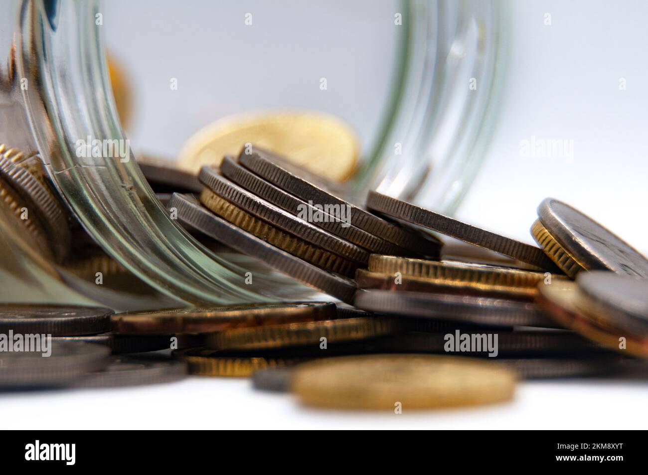 Nahaufnahme von Münzen in einem Glas auf weißem Hintergrund mit anpassbarem Platz für Text oder Ideen. Geschäfts- und Investitionskonzept. Stockfoto