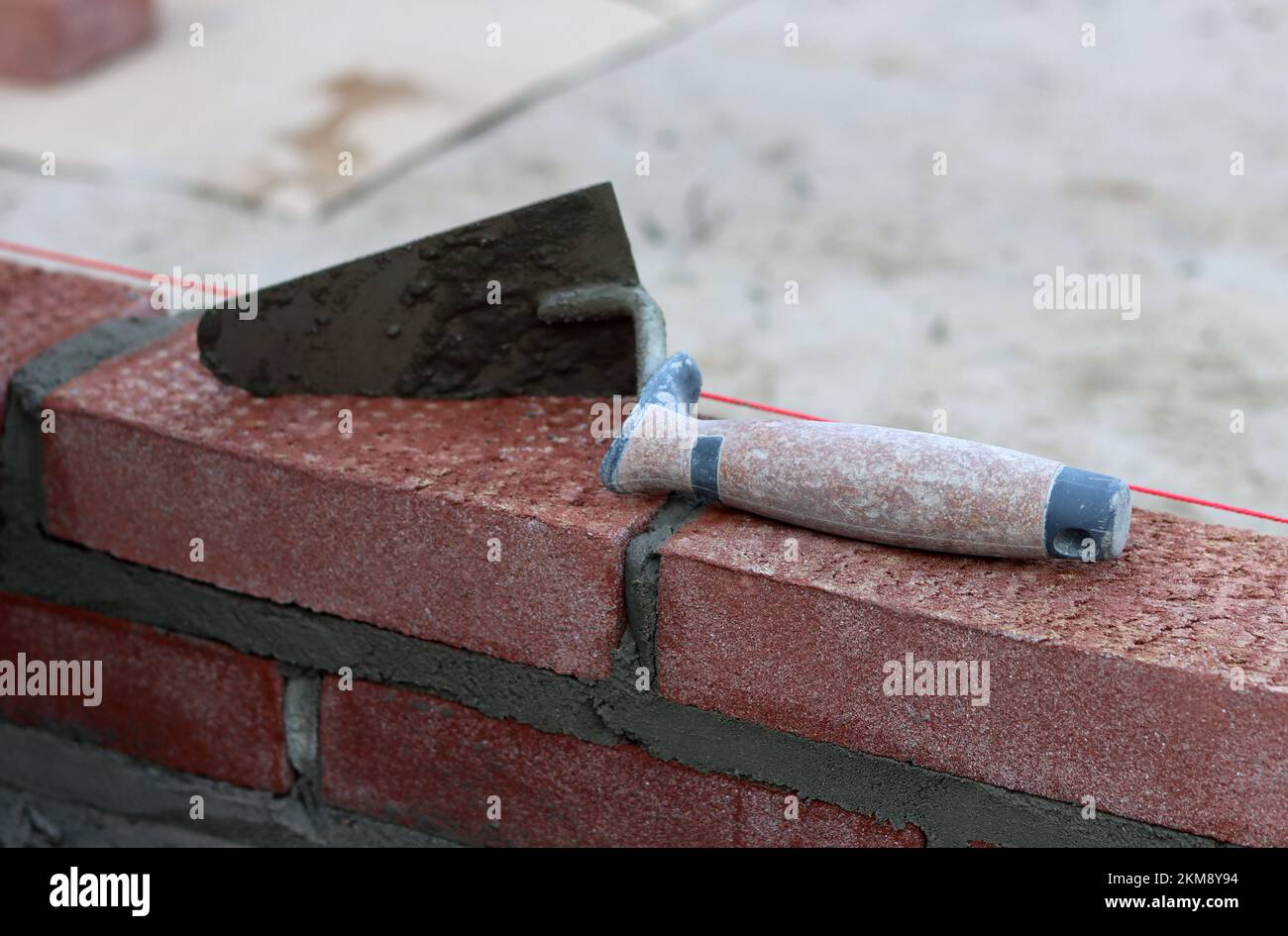 Maurerkelle an einer Wand. Nahaufnahme des Bauwerkzeugs. Baustelle. Stockfoto