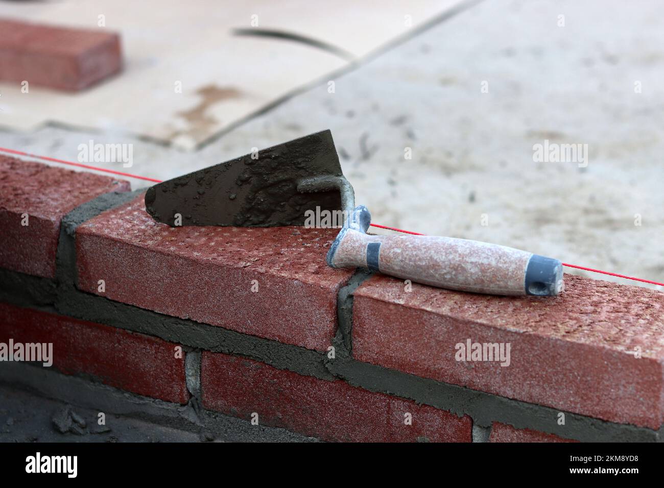 Maurerkelle an einer Wand. Nahaufnahme des Bauwerkzeugs. Baustelle. Stockfoto