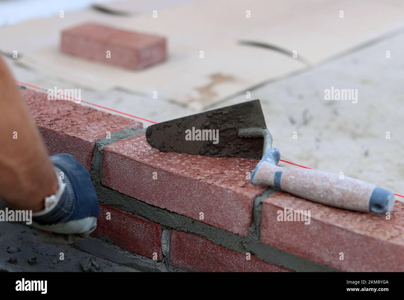 Maurerkelle an einer Wand. Nahaufnahme des Bauwerkzeugs. Baustelle. Stockfoto