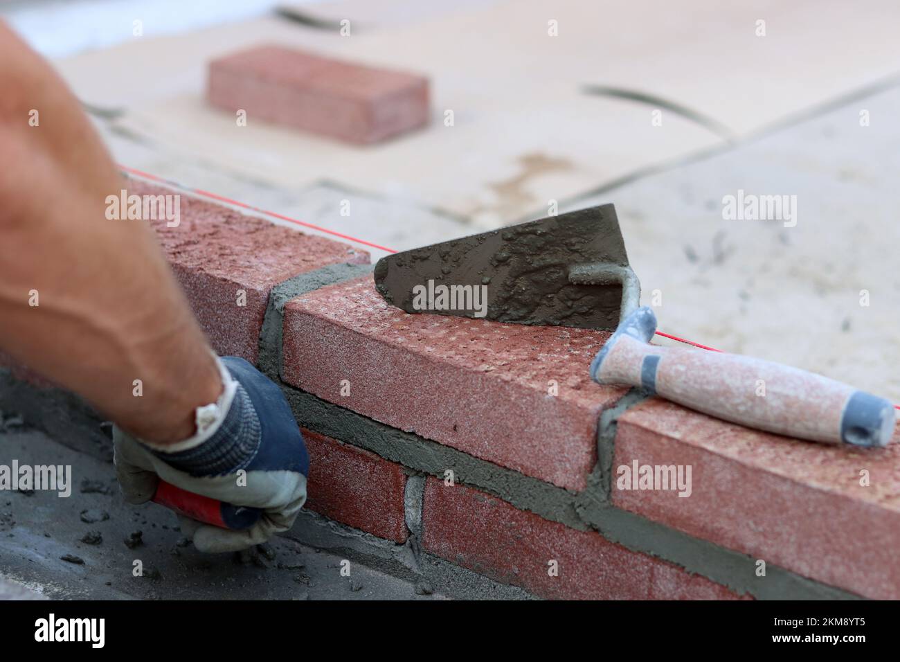 Maurerkelle an einer Wand. Nahaufnahme des Bauwerkzeugs. Baustelle. Stockfoto