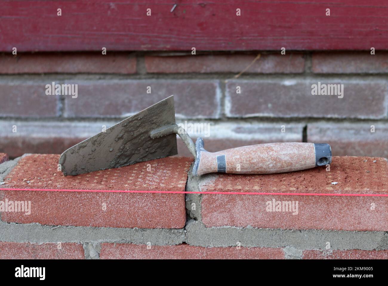 Maurerkelle an einer Wand. Nahaufnahme des Bauwerkzeugs. Baustelle. Stockfoto