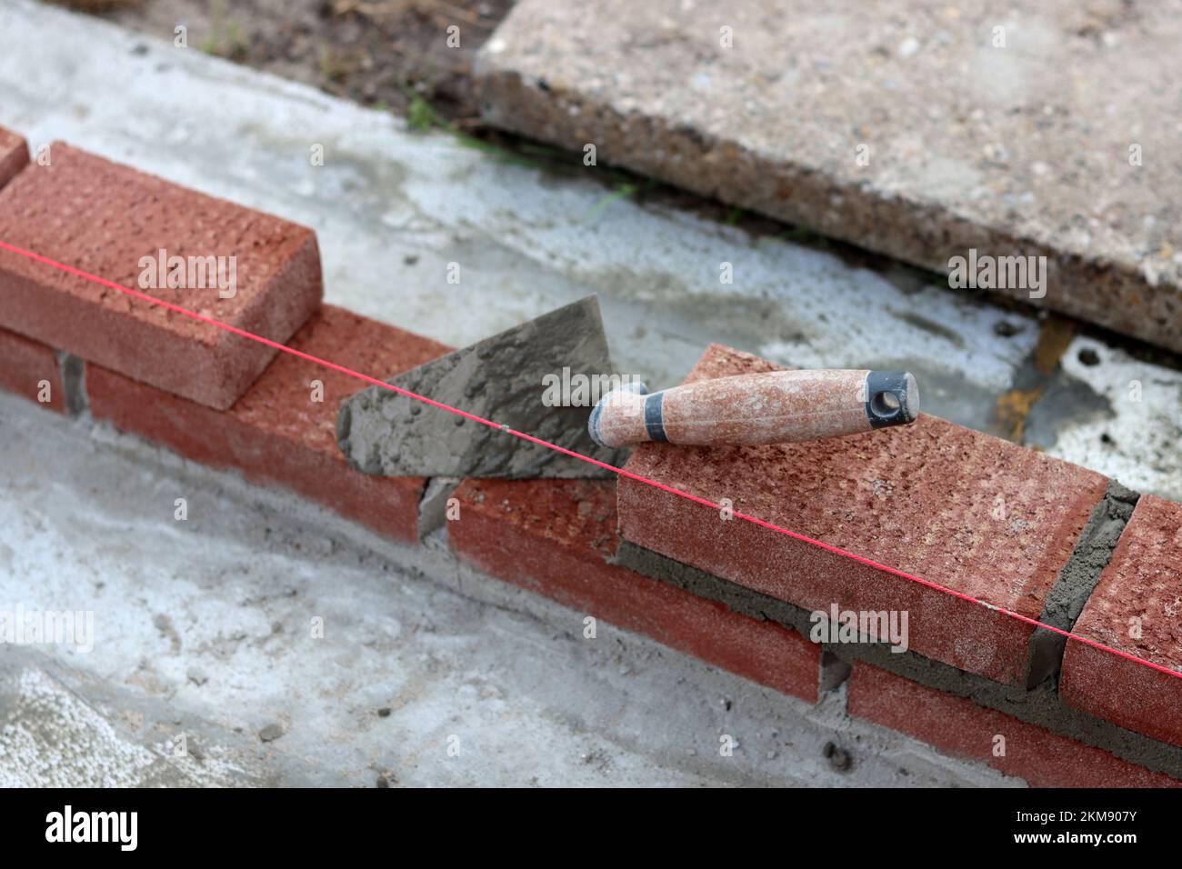 Maurerkelle an einer Wand. Nahaufnahme des Bauwerkzeugs. Baustelle. Stockfoto