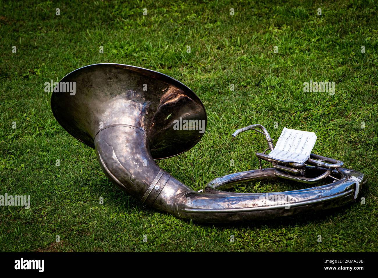 Ein altes Sousaphon mit einem Stück Notenblatt, isoliert auf dem Rasen in einem Park Stockfoto