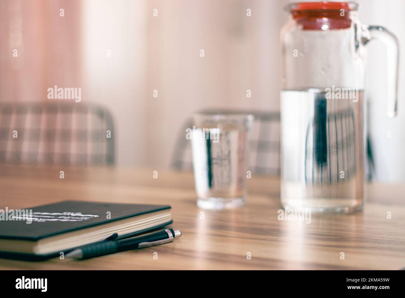 Farbmuster in Pastelltönen, Notizbuch auf Holztisch und eine Kanne Wasser, glass.selective Fokus. Stockfoto