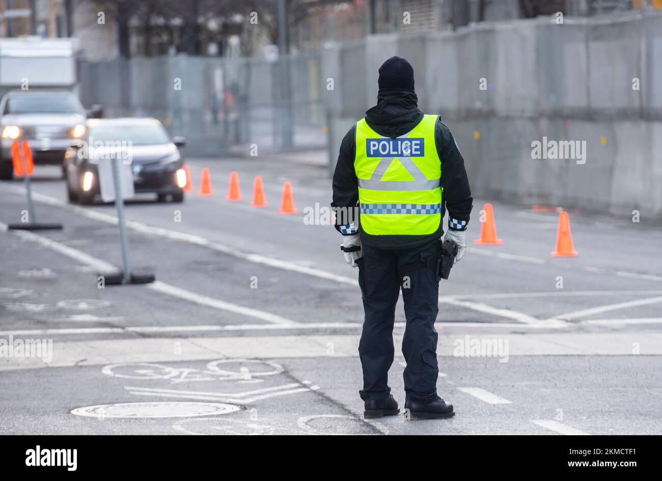 MONTREAL, QUEBEC, KANADA: Ein Polizeibeamter leitet den Verkehr neben einem Zaun, der den Umkreis des Montreal Convention Centre sichert, vor der COP 15, der UN-Konferenz zur Erhaltung der biologischen Vielfalt in Montreal, Quebec, Kanada, Samstag, 26. November, 2022. Die Konferenz findet vom 7. Bis 19. Dezember statt. Foto: Graham Hughes/Freelance Stockfoto