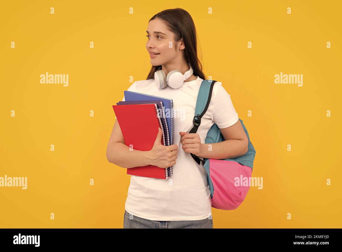 Positive Schüler halten Notebook. Mädchen hält Notebook auf gelbem Hintergrund. Private Lehrerin Stockfoto