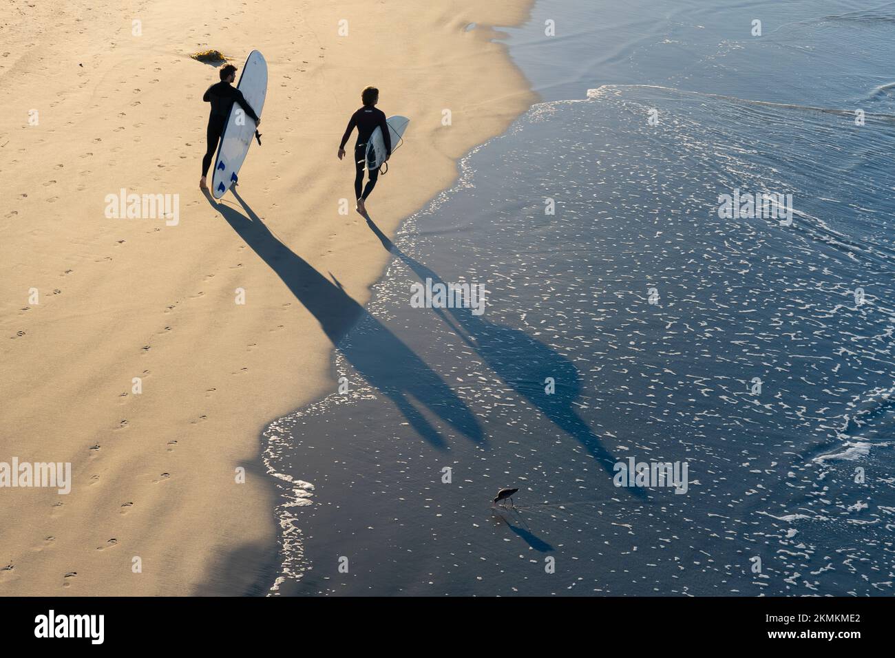 Am Oceanside City Beach in Oceanside, Kalifornien, spazieren zwei Surfer entlang der Küste. Stockfoto