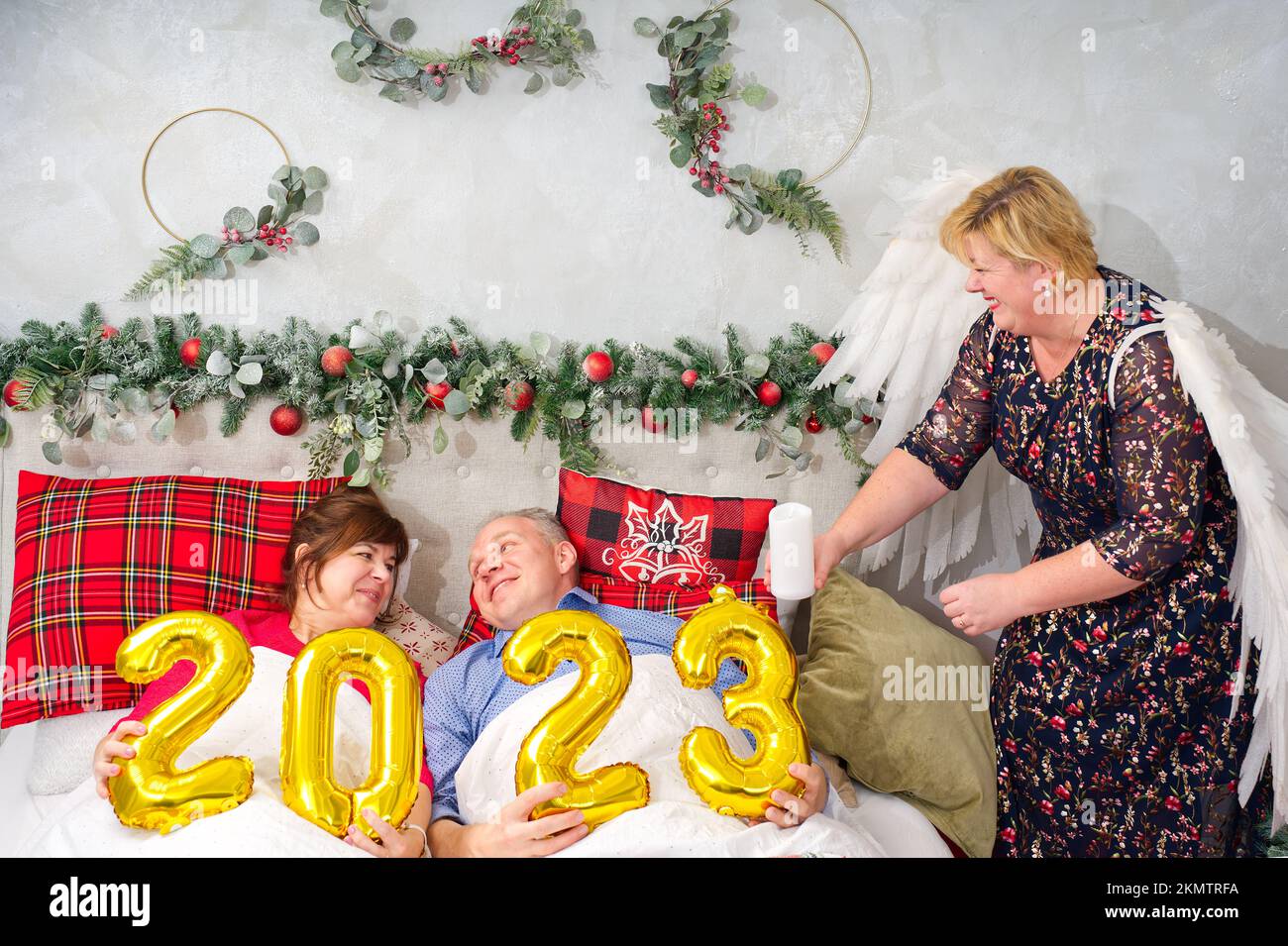 Schönes Paar liegt im Bett und plant, ein Baby zu haben. Weihnachten und frohe Neujahr mit den Zahlen 2023 Stockfoto