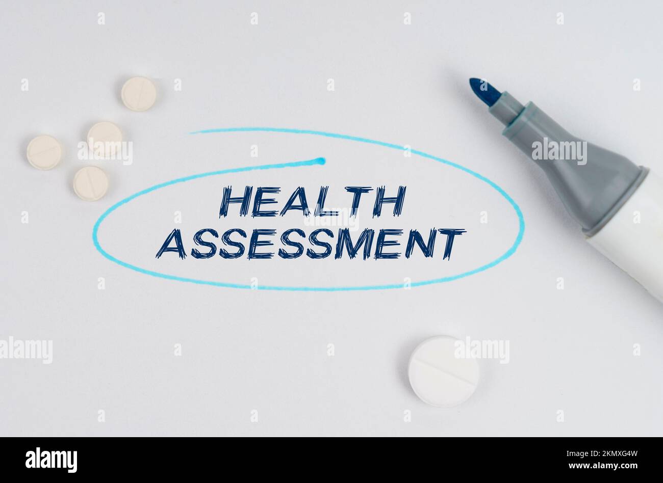 Medizin und Gesundheitskonzept. Auf einem weißen Blatt Papier, Tabletten, einem Marker und einer Aufschrift - GESUNDHEITSBEURTEILUNG durch ein gezogenes Oval angezeigt. Stockfoto