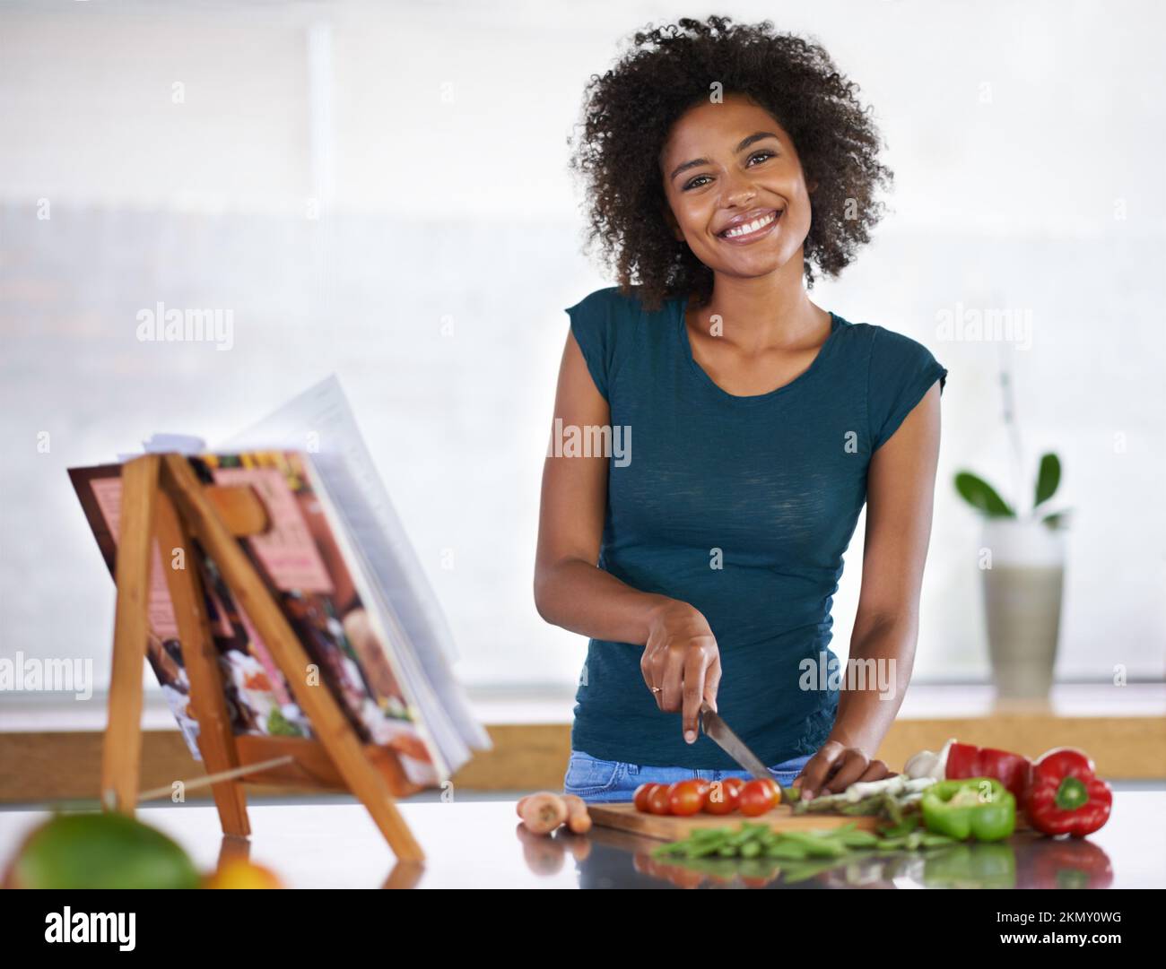 Am glücklichsten, wenn ich koche. Eine junge Frau, die aus einem Rezeptbuch kocht. Stockfoto