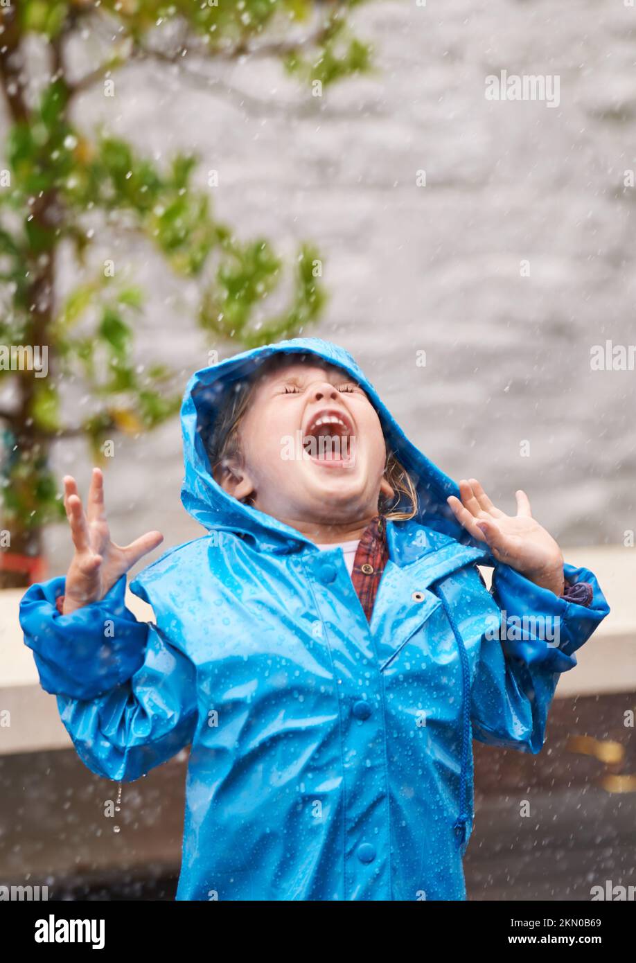Freiheit im Regen. Ein junges Mädchen, das draußen im Regen spielt. Stockfoto